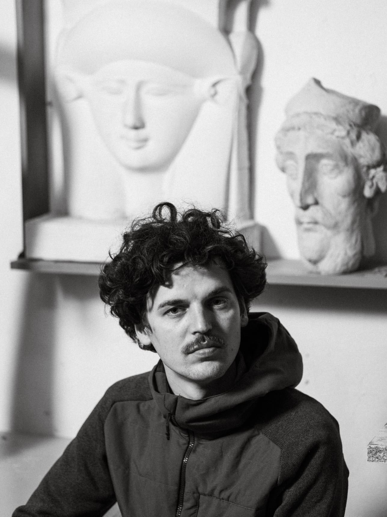 Emanuel Chiriac în atelier, fotografie alb-negru, busturi de ipsos în fundal